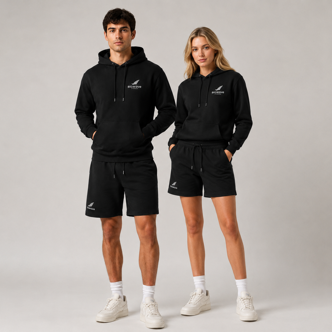 Männliches und weibliches Model tragen den schwarzen BIGWAVE Unisex Hoodie mit Logo beim Fashion Shooting.