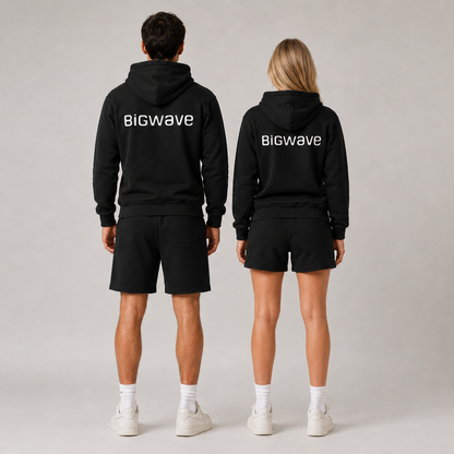 Männliches und weibliches Model tragen den schwarzen BIGWAVE Unisex Hoodie mit Logo beim Fashion Shooting. Zeigen den Backprint vom BIGWAVE Hoodie.